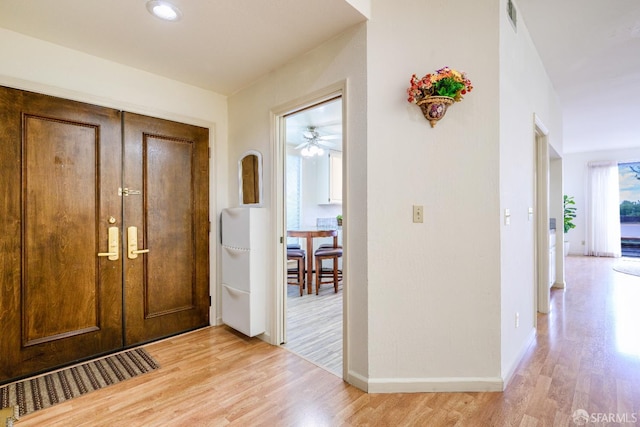 foyer with light wood-type flooring, baseboards, and ceiling fan