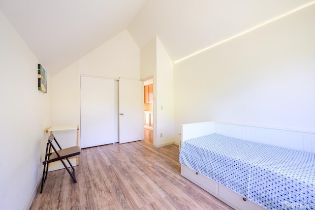 unfurnished bedroom featuring wood finished floors, lofted ceiling, a closet, and baseboards