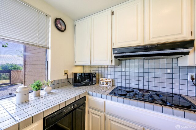 kitchen featuring under cabinet range hood, tile counters, black appliances, and white cabinets