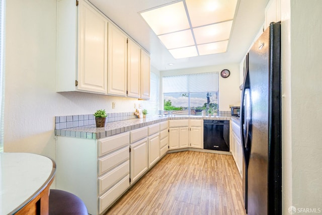 kitchen featuring black appliances, light wood-style floors, tile countertops, and white cabinets