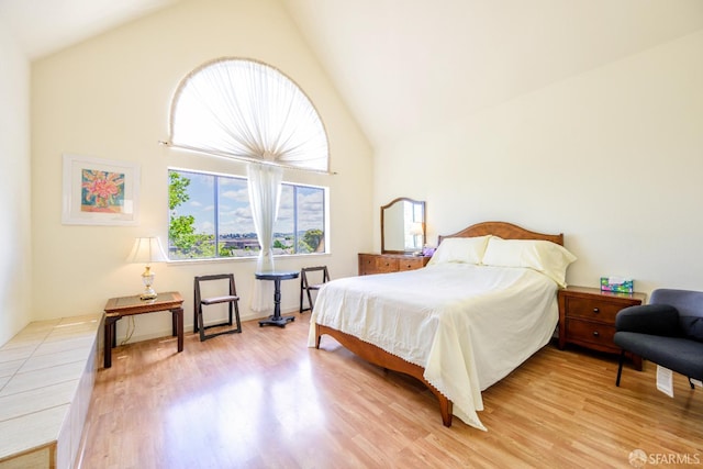 bedroom featuring high vaulted ceiling and light wood-style flooring