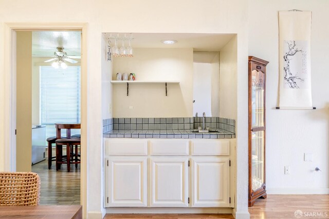 kitchen featuring tile countertops, a ceiling fan, white cabinetry, and light wood-type flooring