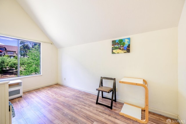 unfurnished room featuring vaulted ceiling, wood finished floors, and baseboards