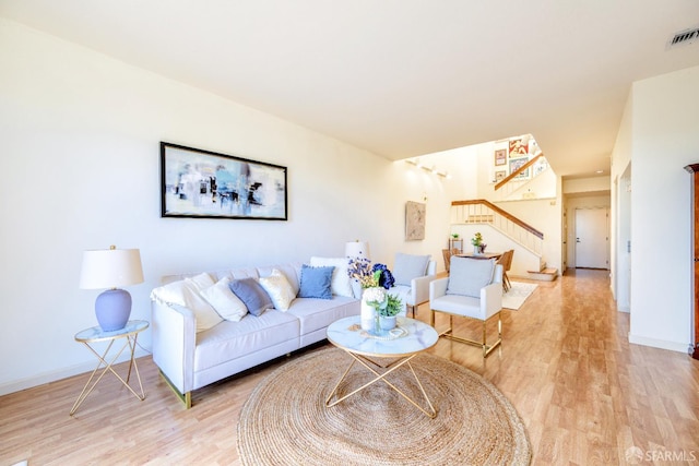 living area with stairs, light wood-style flooring, and baseboards
