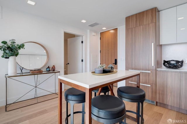 kitchen featuring light hardwood / wood-style flooring, white cabinets, and a kitchen bar