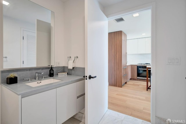 bathroom with vanity, hardwood / wood-style floors, and tasteful backsplash