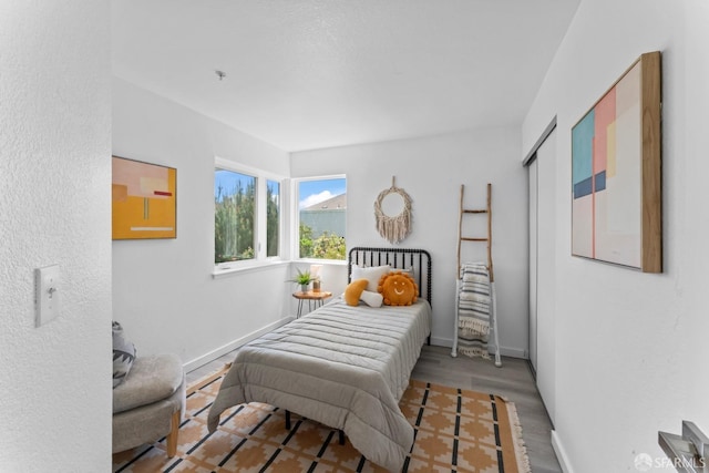 bedroom featuring wood finished floors, baseboards, and a closet