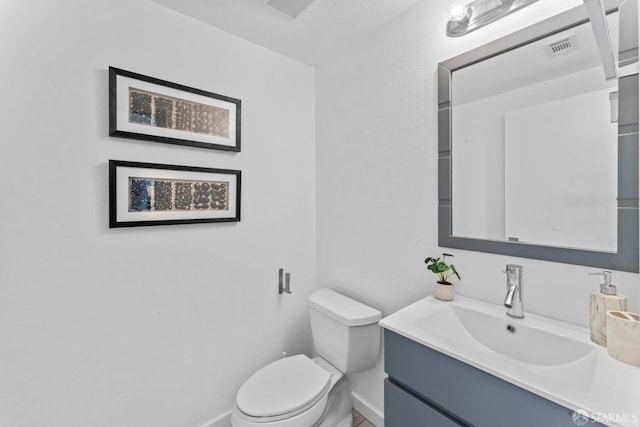 bathroom with visible vents, toilet, vanity, and baseboards