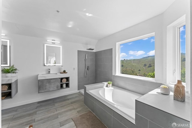 full bath with tiled shower, wood finished floors, a garden tub, and a wealth of natural light