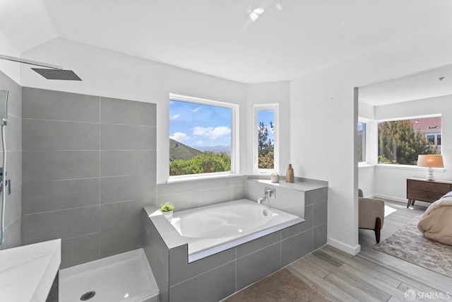 full bathroom featuring plenty of natural light, tiled shower, and wood finished floors