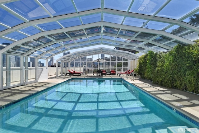 view of swimming pool with glass enclosure and a patio area