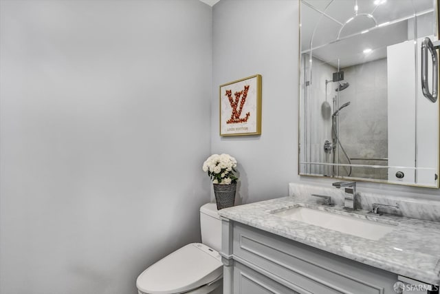 bathroom with tiled shower, vanity, and toilet