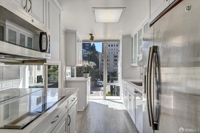 kitchen featuring stainless steel appliances, plenty of natural light, dark hardwood / wood-style floors, and white cabinetry