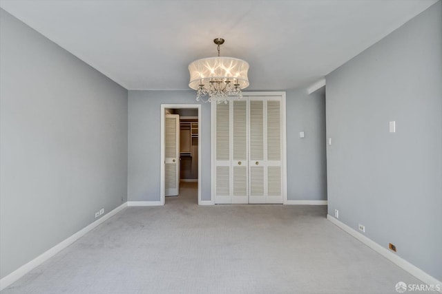 spare room featuring light carpet and a chandelier