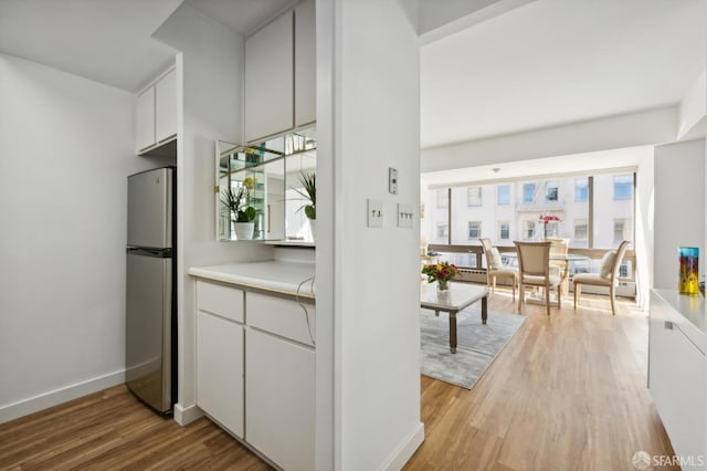 kitchen with light hardwood / wood-style floors, stainless steel fridge, and white cabinetry