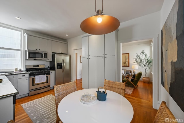 1630 Clay St Unit 4, San Francisco, CA 94109 - kitchen featuring appliances with stainless steel finishes, light wood-style flooring, gray cabinets, pendant lighting, and dark countertops