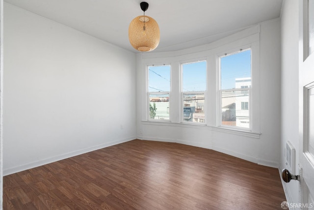 empty room featuring baseboards and dark wood-style floors