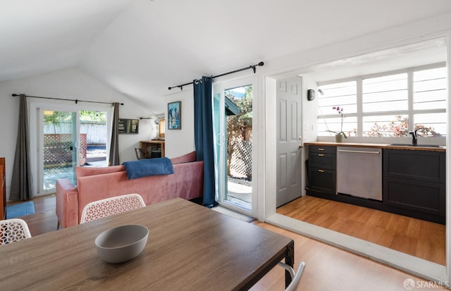 dining space with vaulted ceiling and light wood-style flooring