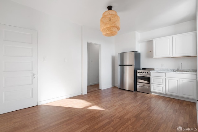 kitchen featuring light wood-type flooring, a sink, white cabinetry, stainless steel appliances, and light countertops