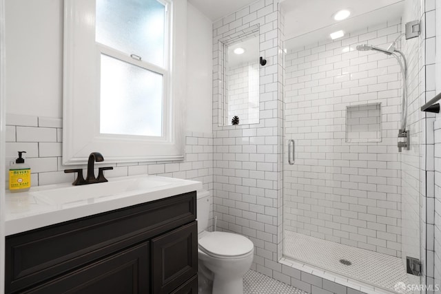 bathroom featuring a shower stall, tile walls, vanity, and toilet