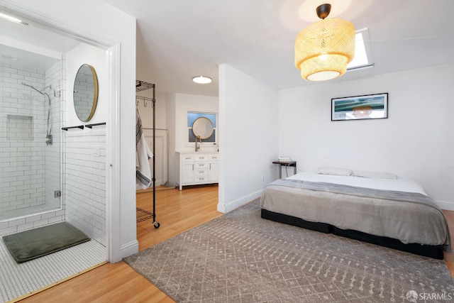 bedroom featuring wood finished floors, baseboards, and connected bathroom