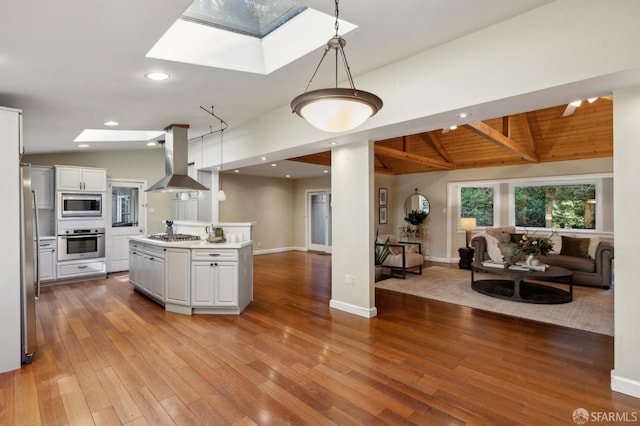 kitchen featuring decorative light fixtures, a skylight, appliances with stainless steel finishes, and island exhaust hood