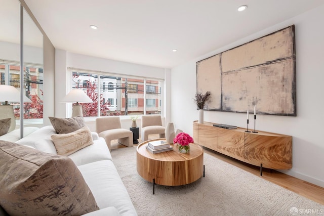 living area with baseboards, wood finished floors, and recessed lighting