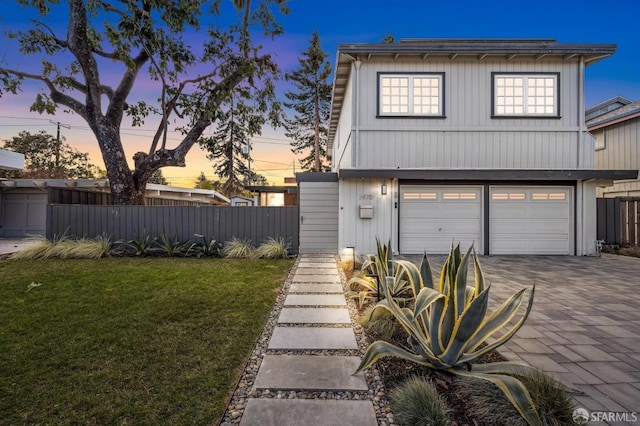 view of front of home featuring decorative driveway, an attached garage, fence, and a front yard