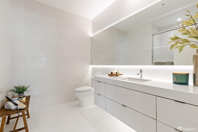 bathroom featuring vanity, a shower, tile patterned flooring, toilet, and tile walls