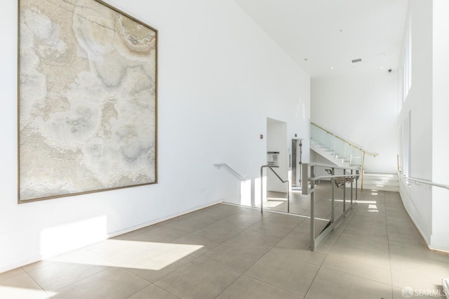 stairs with tile patterned flooring and a towering ceiling