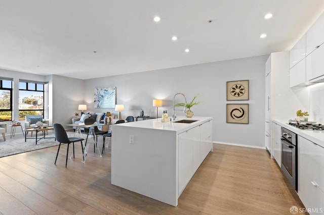 kitchen with light hardwood / wood-style flooring, stainless steel appliances, white cabinetry, and sink