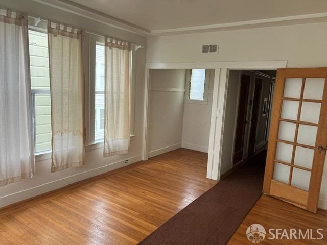 unfurnished room with wood finished floors, visible vents, and baseboards
