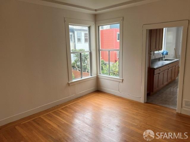 empty room with a sink, light wood finished floors, and baseboards