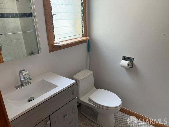bathroom with vanity, toilet, a tile shower, and tile patterned flooring