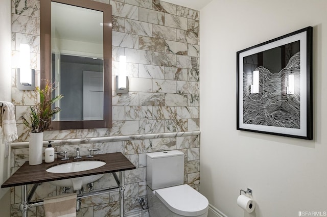 bathroom with sink, tile walls, and toilet