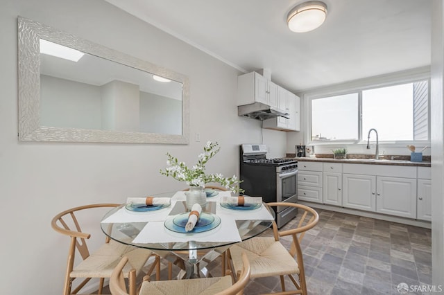 141 Cambridge St, San Francisco, CA 94134 - kitchen featuring stainless steel range with gas stovetop, a sink, under cabinet range hood, white cabinetry, and stone finish floors