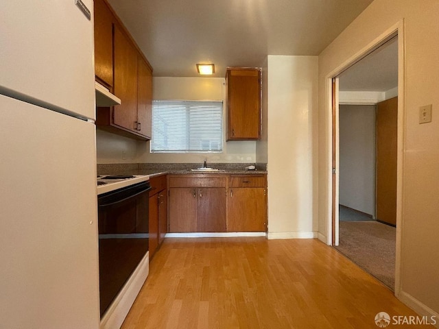 kitchen featuring light wood-type flooring, electric range, white refrigerator, and sink