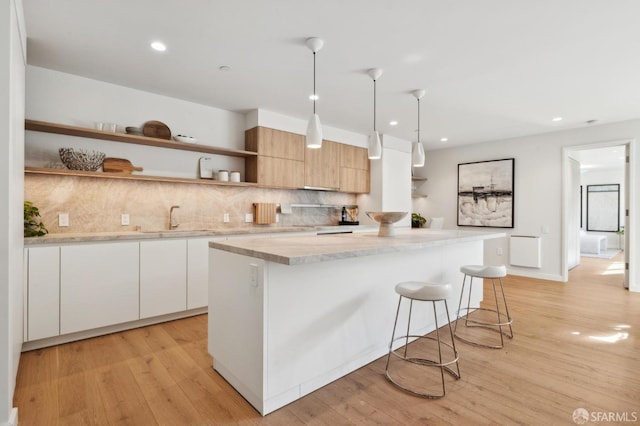 kitchen with a center island, sink, hanging light fixtures, and white cabinets