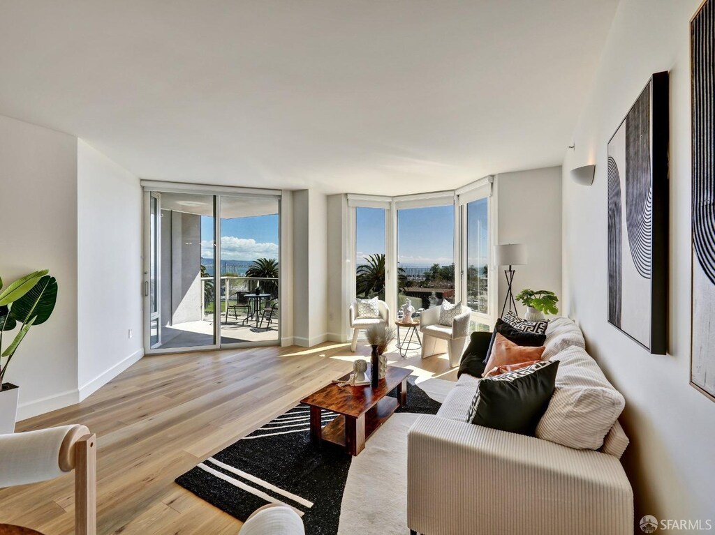 living room with a wall of windows, wood finished floors, and baseboards