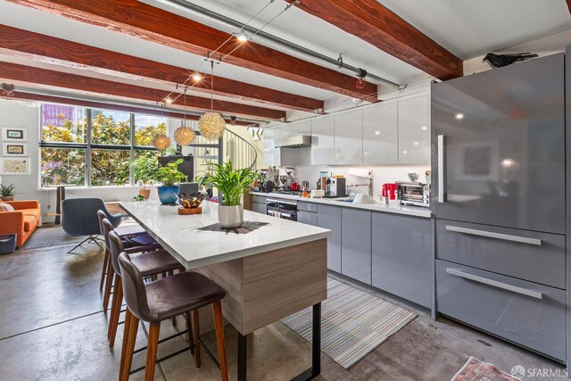 701 Pennsylvania Ave Unit 107, San Francisco, CA 94107 - kitchen featuring freestanding refrigerator, finished concrete flooring, a kitchen breakfast bar, modern cabinets, and white cabinets