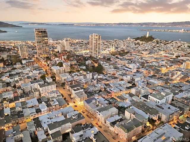 aerial view at dusk featuring a water view and a view of city