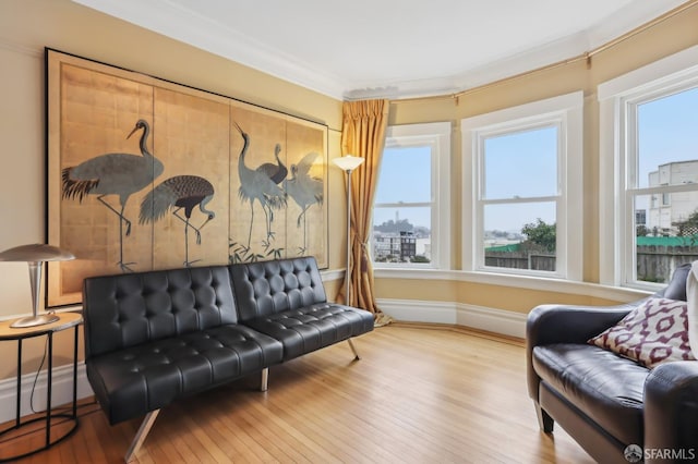 living area featuring baseboards, crown molding, and hardwood / wood-style floors