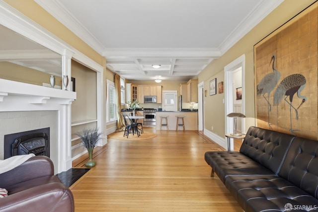 living area featuring light wood-style floors, coffered ceiling, a fireplace, and crown molding