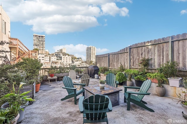 view of patio / terrace featuring a city view, a fenced backyard, and grilling area