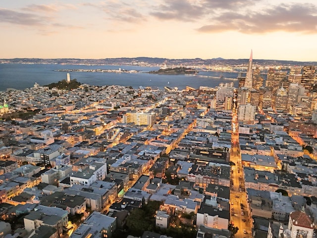 aerial view at dusk featuring a view of city and a water view