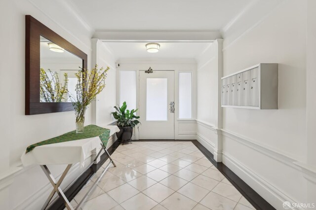 interior space featuring light tile patterned floors, plenty of natural light, mail area, and crown molding