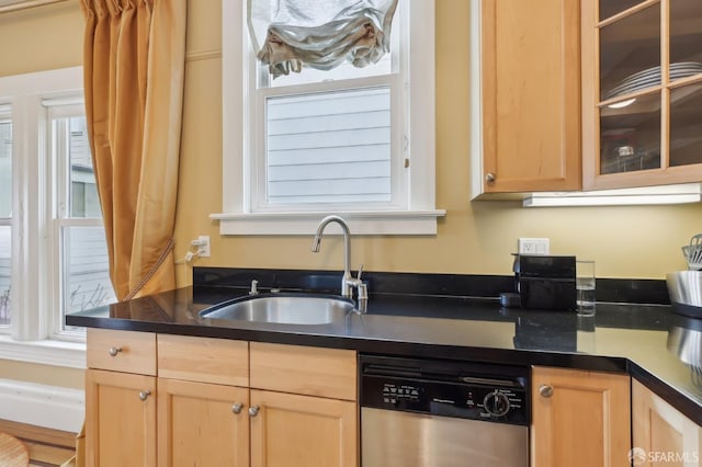 kitchen with dark countertops, light brown cabinets, a sink, and stainless steel dishwasher