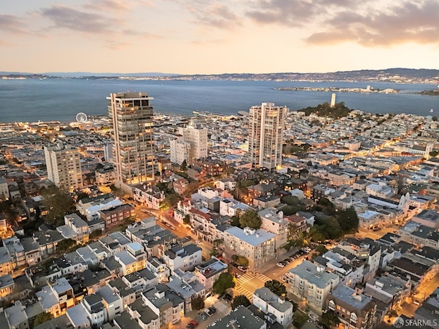 aerial view at dusk featuring a water view and a city view