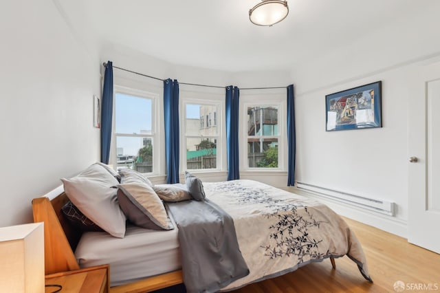 bedroom with a baseboard radiator and wood finished floors