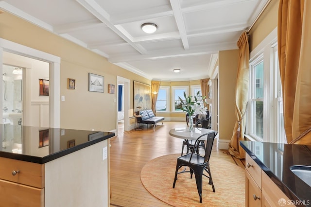 dining space featuring beam ceiling, light wood-style floors, ornamental molding, coffered ceiling, and baseboards